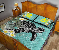 Teal quilt bed set with black-and-white turtle artwork, white plumeria flowers, and yellow squares