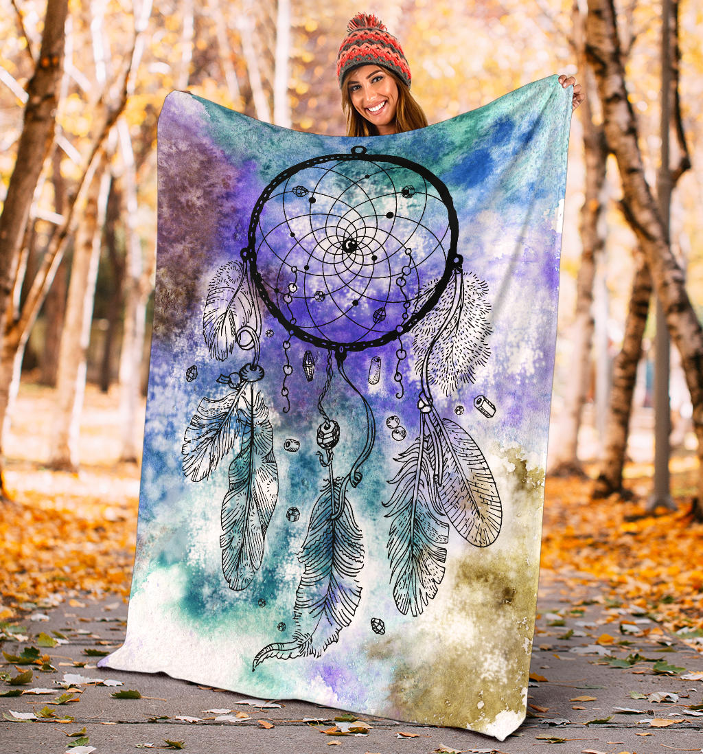 Multicolor dream catcher blanket held outdoors, featuring purple-blue web and feather print