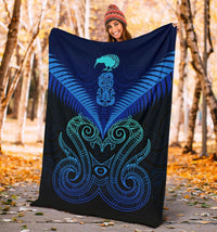 Blue Maori manaia blanket with teal and black tribal wings pattern, held outdoors