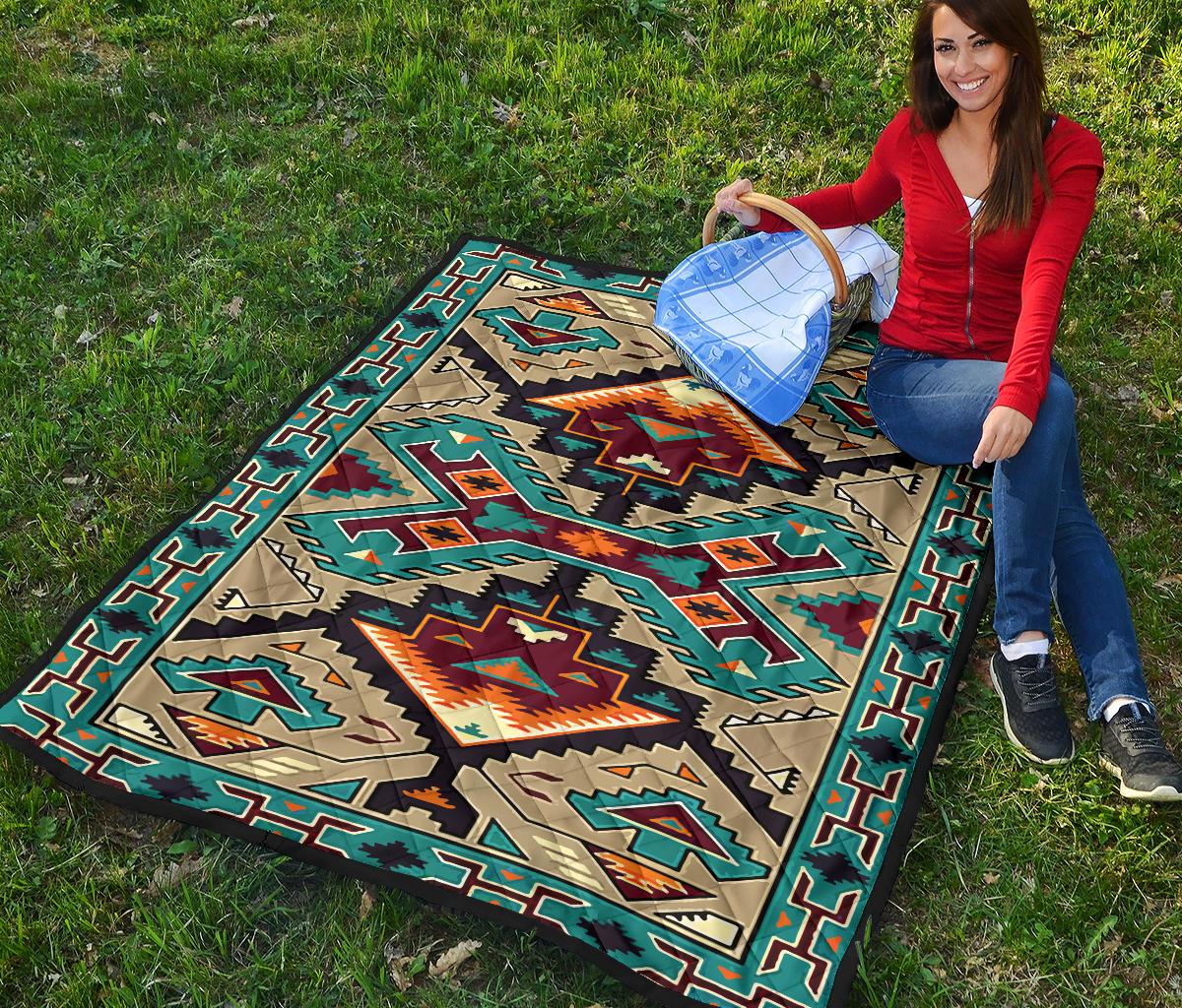 Multicolor geometric quilt laid on grass, teal border with diamond and star accents