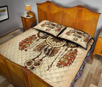 Tan dreamcatcher quilt bed set with two pillows on wood bed, bold feather and hoop motifs