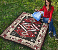 Quilt laid on grass with red and dark gray center diamond and star blocks border.