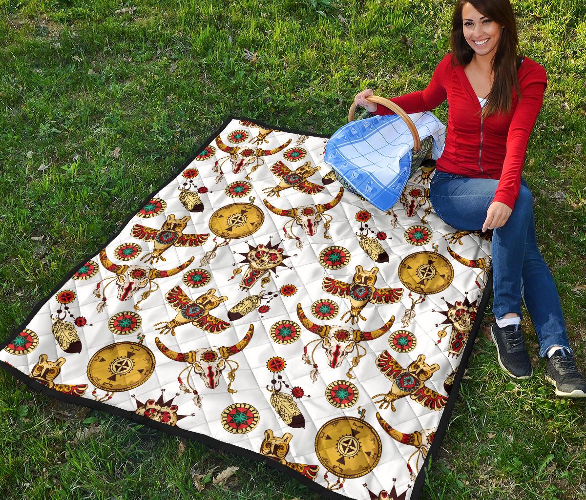 Multicolor Native American totems quilt laid flat on grass with detailed bull and feather motifs