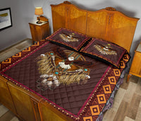 Burgundy dreamcatcher quilt with gold-and-teal bird design and geometric trim, two pillows