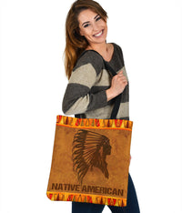 Brown tote with Native American text banner, black headdress image, orange tribal border and strap