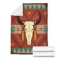 Folded multicolor bison skull blanket with white plush backing; green and teal geometric trim