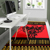 Red area rug showing black bird emblem with yellow zigzag and swirl border strips