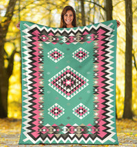 Turquoise geometric blanket with pink, black, and white diamond motifs and zigzag trim