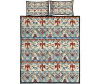 Light blue quilt bed set with red, tan, and navy geometric stripes, arrows, and diamonds