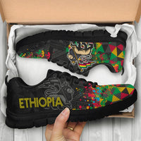 Black Ethiopia sneakers in box, colorful geometric side panels and large yellow ETHIOPIA logo