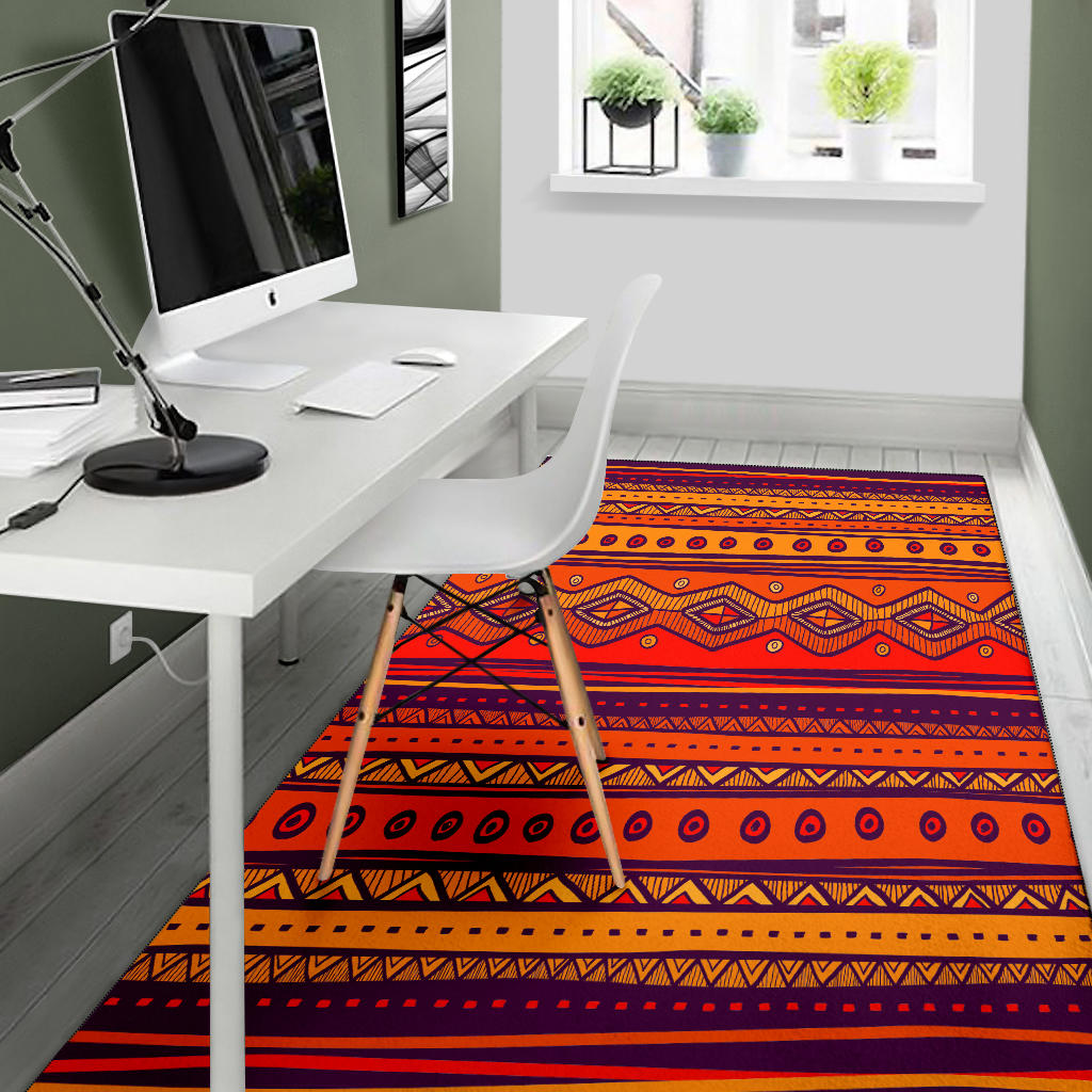 Orange patterned area rug featuring tribal bands, circles, and chevron shapes with dark trim.