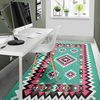 Teal geometric area rug with pink, black and white shapes and bold zigzag edge