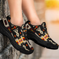 Pair of black chunky sneakers on feet, Native-style geometric print, lace-up thick sole