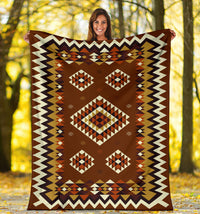 Brown patterned blanket held flat, with diamond motifs and white zigzag border
