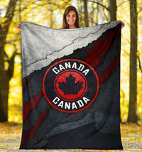 Folded Canada blanket, grunge flag map and red maple-leaf emblem on black