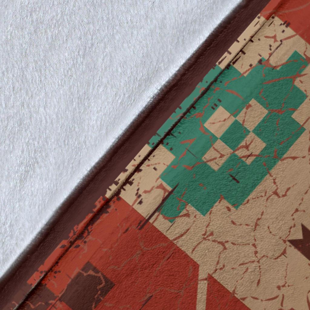 Close-up of multicolor blanket edge: red, green, beige geometric pattern with brown trim