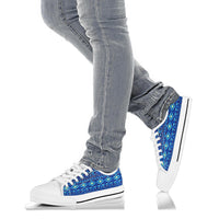 White low-top sneakers with blue geometric pattern worn with light blue jeans