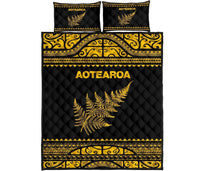 Black quilt with two pillows, yellow Aotearoa logo, fern graphic and Maori band