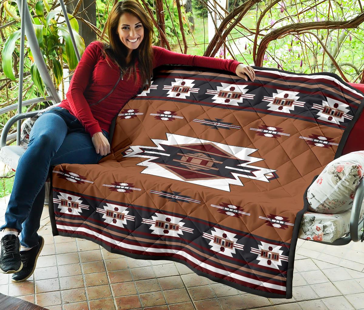 Brown quilt draped on chair with geometric stripe motifs and central red diamond emblem