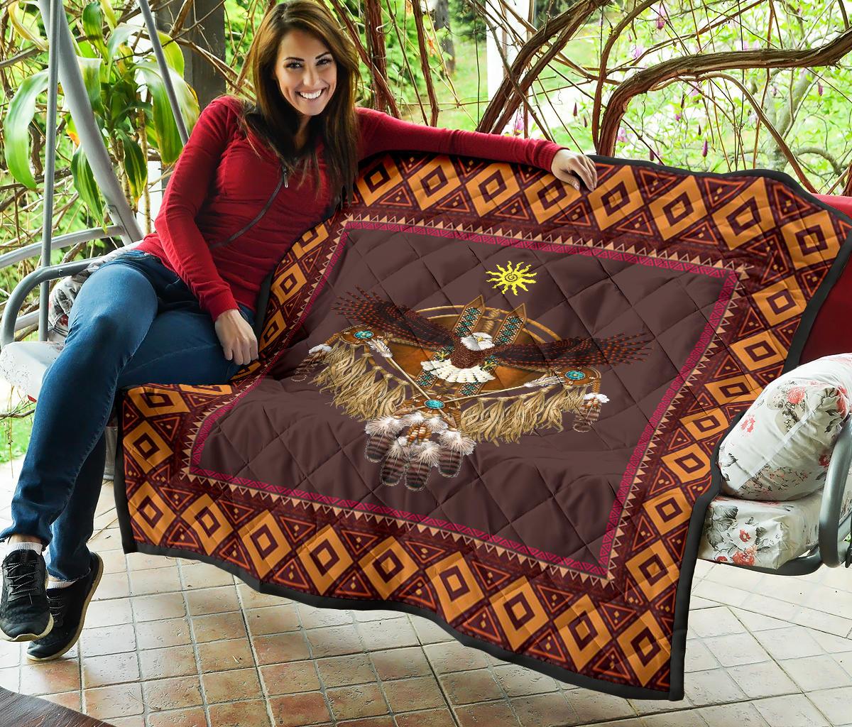 Native-style quilt draped on patio seating, maroon center featuring eagle and sun emblem