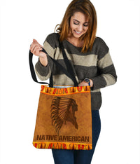 Brown tote bag with black headdress print, orange tribal border, and centered Native American wording