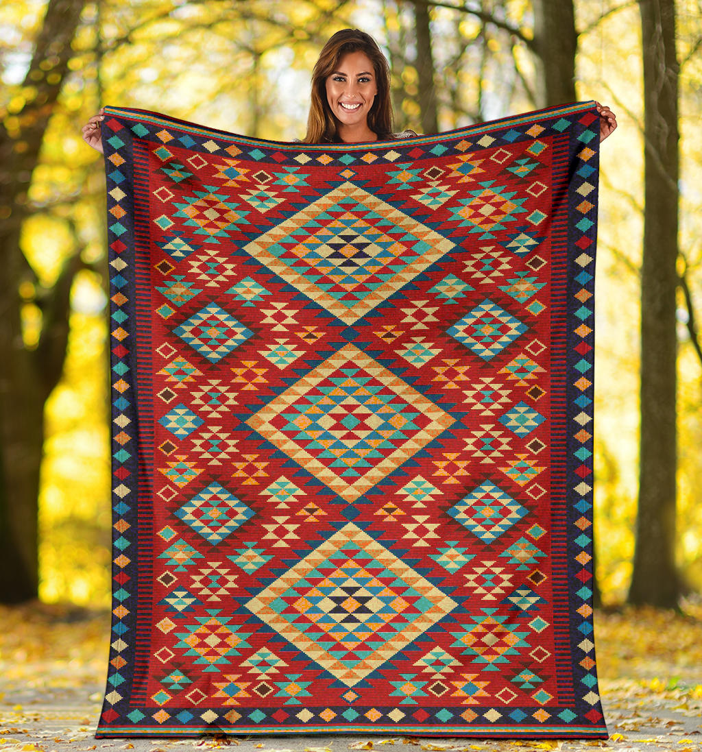 Geometric throw blanket spread outdoors, red teal and green diamond shapes