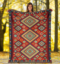 Geometric throw blanket spread outdoors, red teal and green diamond shapes