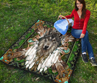 Wolf mandala quilt laid on grass, green multicolor tribal print with black border