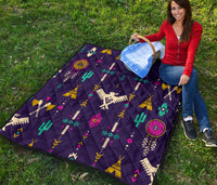 Blue quilt with Native-inspired geometric thunderbird pattern, multicolor accents on grass