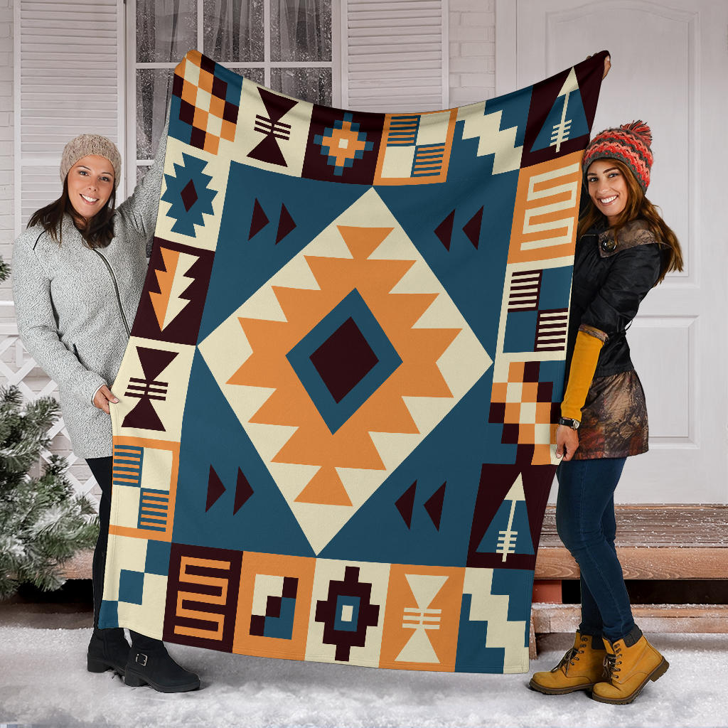 Navy arrow pattern blanket held by two people, cream diamond center with orange and maroon shapes