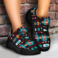 Black chunky lace-up sneakers with neon blue Aztec-style pattern, shown with full pair on feet