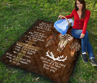 Brown quilt spread out outdoors with bison head graphic, feathers, and white sayings