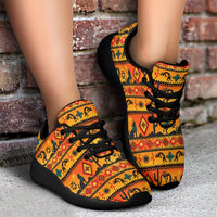 Native motif sport sneakers with black laces and black heel trim, standing on ground