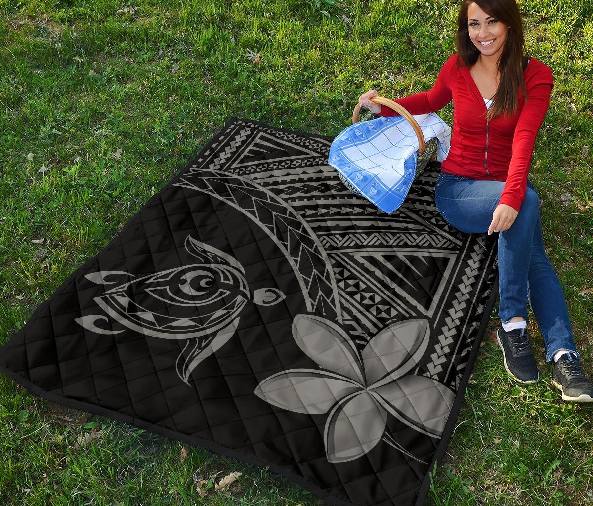Folded black-and-grey Hawaiian quilt with turtle and plumeria graphic, quilted diamond texture