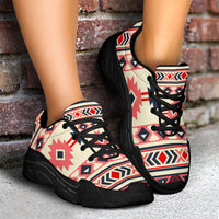 Chunky sneakers on feet, angled view: cream upper with pink/navy pattern, black laces, black sole