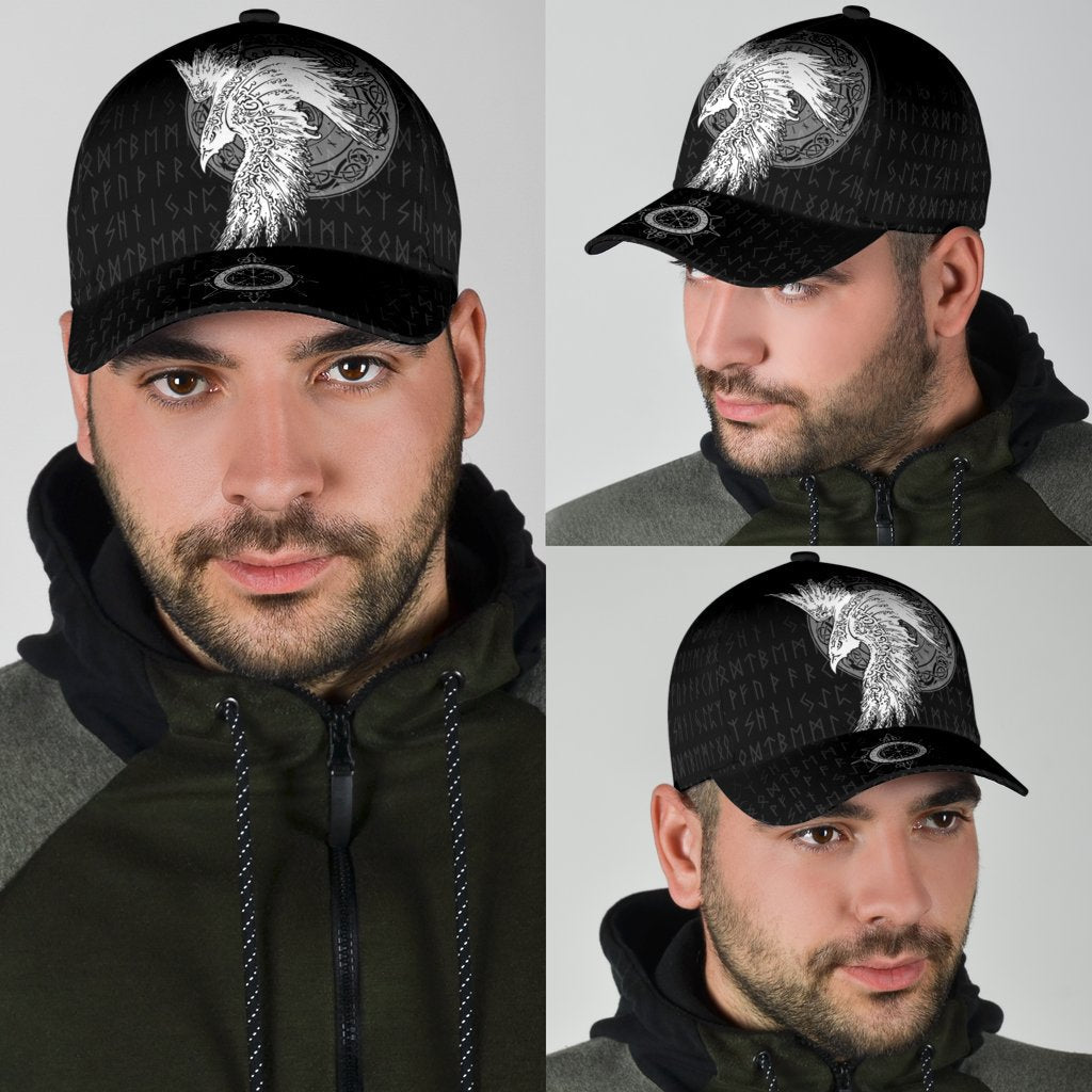 Black cap worn by man with white raven graphic, seen from side