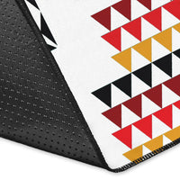 Corner close-up of geometric rug edge: black backing with white, red, and yellow triangles