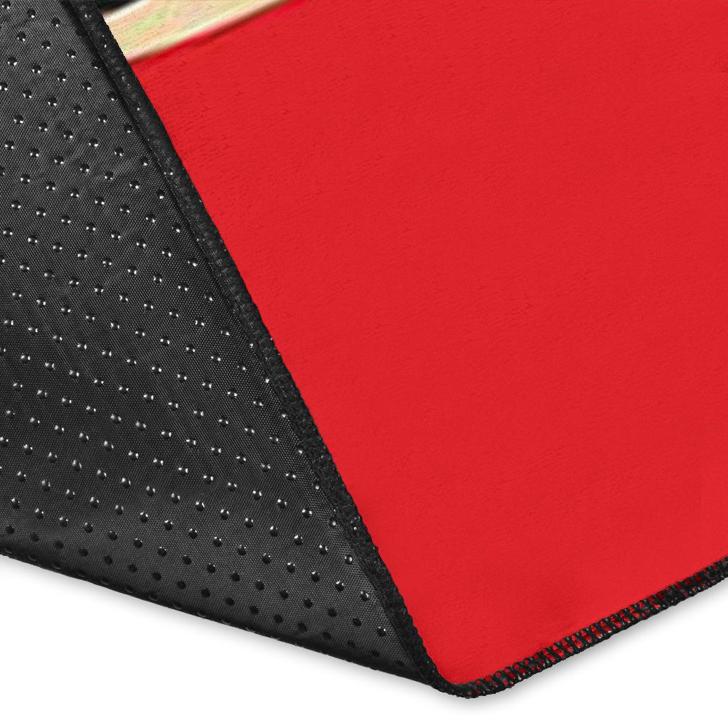 Corner close-up of red area rug with black textured backing and red stitched edge