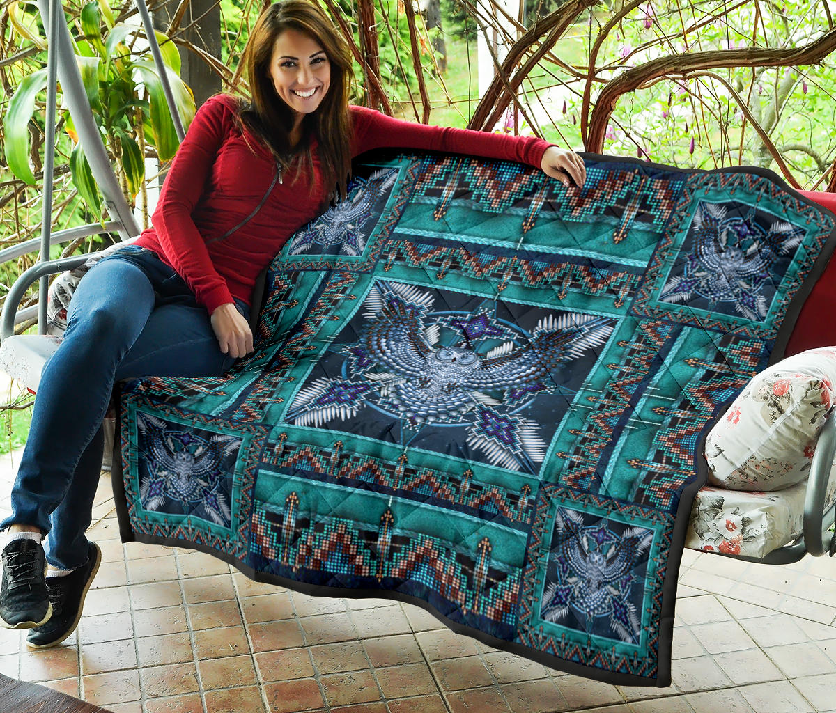 Teal and navy quilt draped over surface, featuring blue mandala center and corner bird motifs