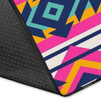 Close-up of geometric area rug edge with black textured backing and bright pink navy shapes.