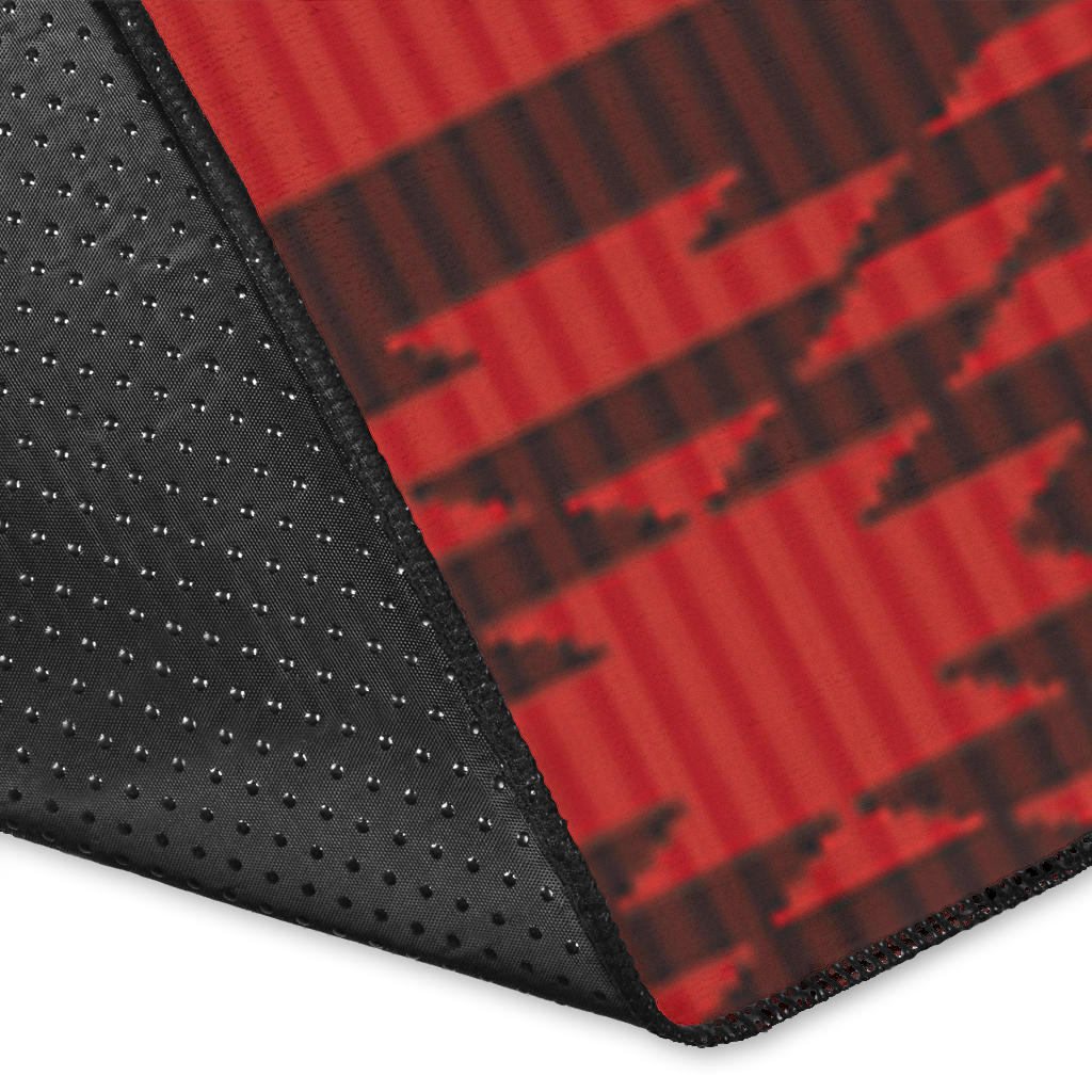Close-up of red geometric rug corner with black grippy backing and dotted texture.