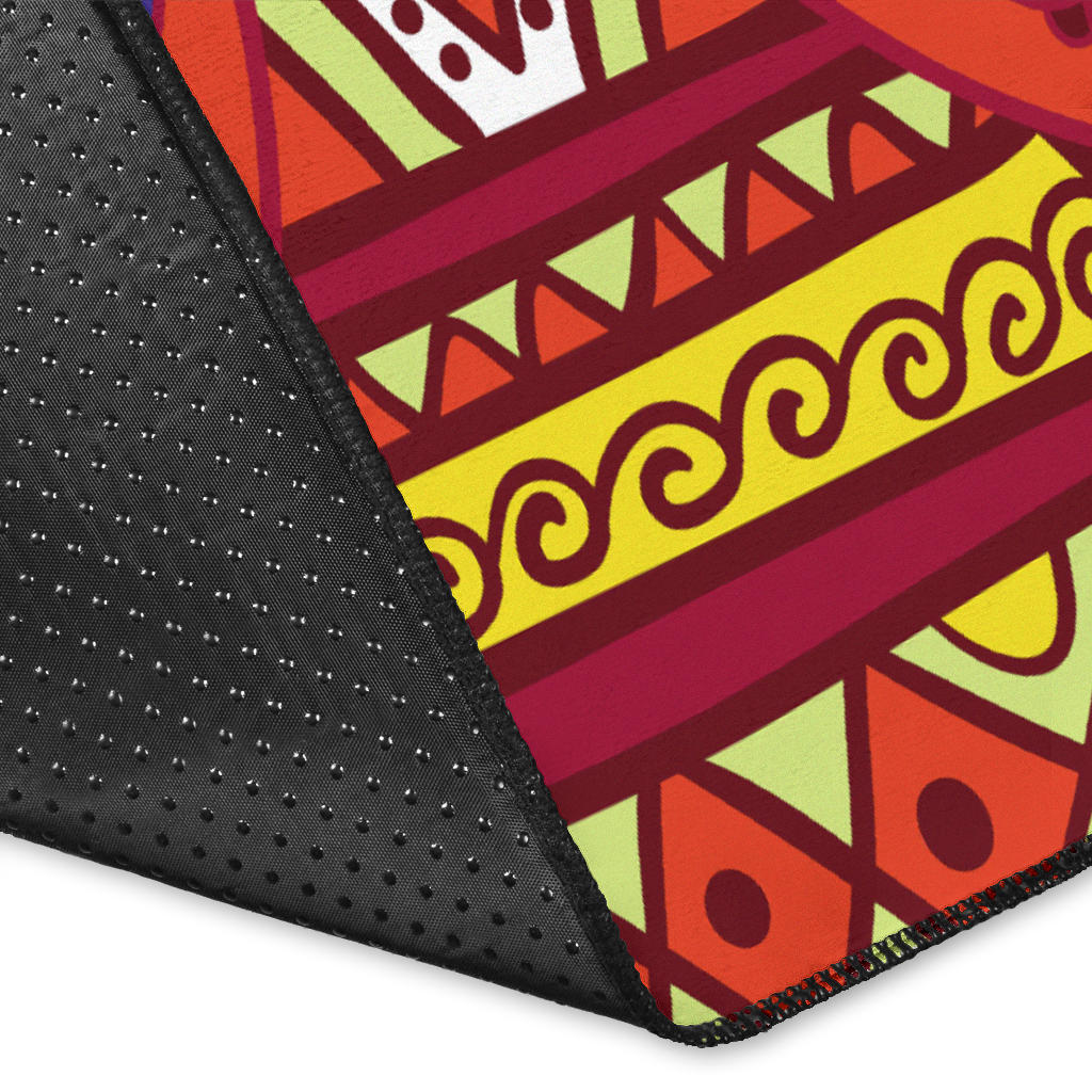 Rug corner close-up: black border with colorful geometric bands and winged emblem details