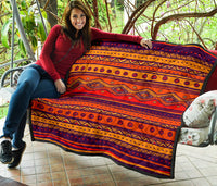 Orange quilt draped over a chair with navy and black diamond patterns and striped borders