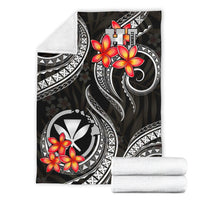 Black blanket with red plumeria, white tribal patterns; rolled white backing visible