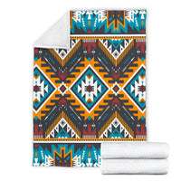 Folded Aztec geometric blanket with rolled white blankets, navy, teal, orange, red, and white motifs