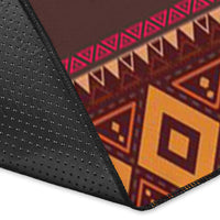 Corner detail of dreamcatcher area rug, textured dark backing with orange-red pattern