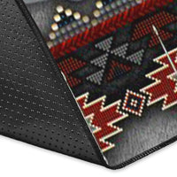 Close-up of rug corner showing dark fabric texture and red/cream geometric trim with dots
