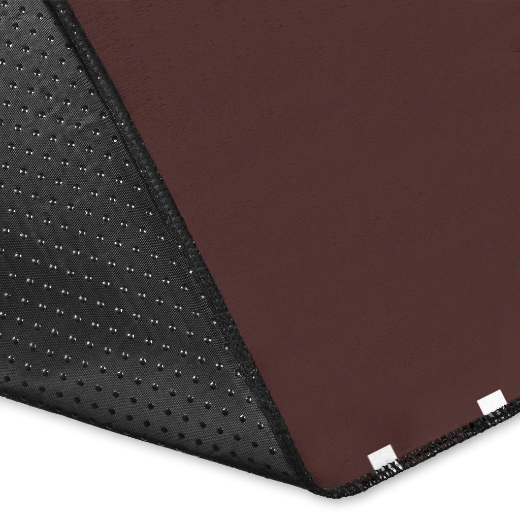 Rug corner close-up: dark textured backing with stitched edge and brown top surface