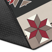 Corner close-up of tribal rug with black fabric edge, red gray starburst pattern, cream