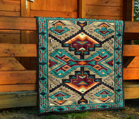 Quilt displayed on wooden exterior, multicolor geometric Native-style design with teal trim